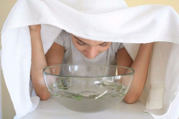 Sau khi đun nước xông, bạn dùng khăn tắm trùm qua đầu trong 10 - 20 phút, thi thoảng dùng đũa khoắng nước để hơi nước tỏa ra đều nhất. Ảnh: anhp.