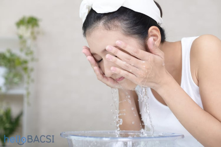Tiếp theo, bạn vắt nước muối sinh lý ở bông tẩy trang rồi thoa đều lên toàn khuôn mặt kết hợp với massage nhẹ nhàng trong 2 - 3 phút trước khi rửa lại với nước. Ảnh: hellobacsi.