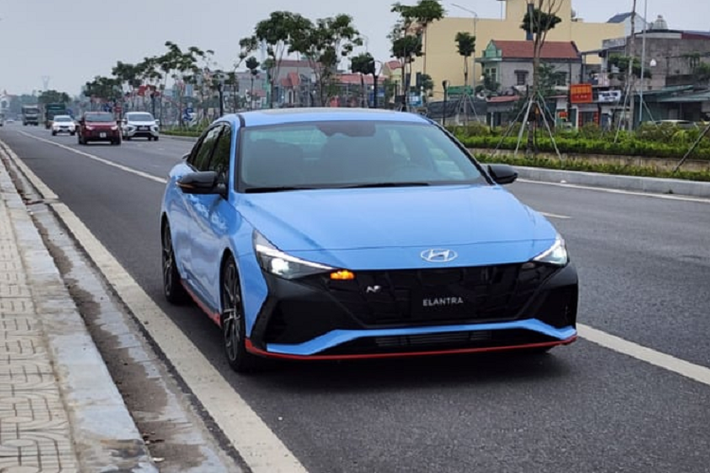 Phần đầu xe Elantra N 2023 gây ấn tượng với mặt ca lăng và hốc gió trước hầm hố, thể thao hơn. Xe được trang bị dàn nhựa để chia cách lưới tản nhiệt và 3 hốc gió. Bên cạnh đó, Elantra N có thêm 1 cánh lướt gió trước và bên hông. Mâm xe đa chấu 19 inch sơn hai màu, đi kèm cùm phanh màu đỏ nổi bật.