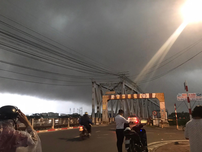 Cơn mưa đến bất chợt khiến người dân phải dừng giữa đường để mặc áo mưa.