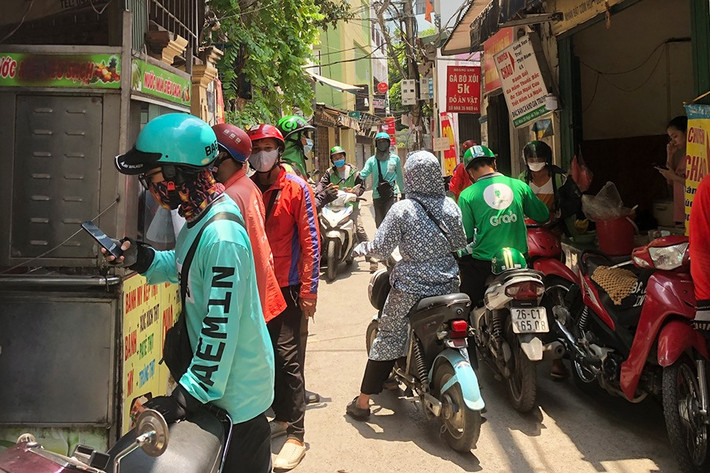 Trước diễn biến phức tạp của dịch COVID-19 trên địa bàn, Hà Nội yêu cầu từ 0h ngày 13.7, dừng tất cả hoạt động kinh doanh dịch vụ không thiết yếu phục vụ công tác phòng, chống dịch COVID-19: Nhà hàng, cơ sở dịch vụ ăn, uống tại chỗ (chỉ cho phép bán hàng mang về), các cửa hàng cắt tóc, gội đầu. Theo ghi nhận của phóng viên trưa 13.7, rất nhiều cửa hàng trong tình trạng quá tải đơn hàng, shipper xếp hàng dài trước cửa để nhận đồ ăn.