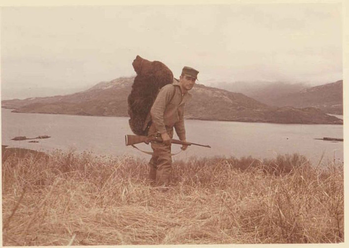 Một thợ săn vùng Kodiak, Alaska (Mỹ) cõng trên lưng chiến lợi phẩm là một con gấu nặng hơn 90kg trong khi tay vẫn cầm súng đã dùng để giết hại nó.