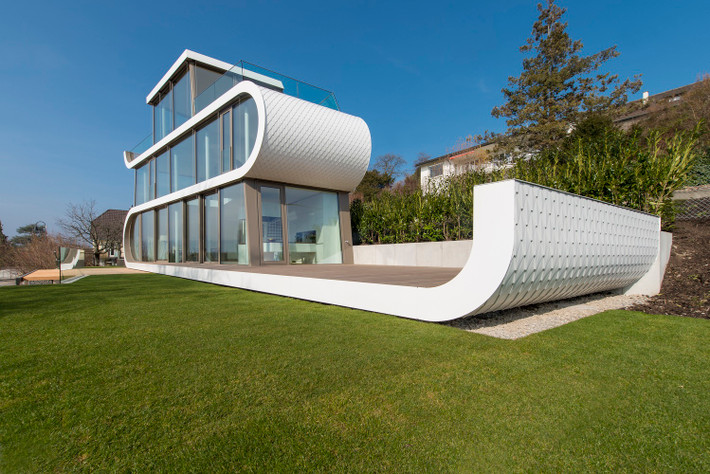 Nằm cạnh hồ Zurich (Thụy Sĩ), ngôi nhà hình chữ S màu trắng tinh khôi này tọa lạc trên một khu có hình tam giác hẹp, nằm kẹp giữa đường xe lửa và đường lớn.