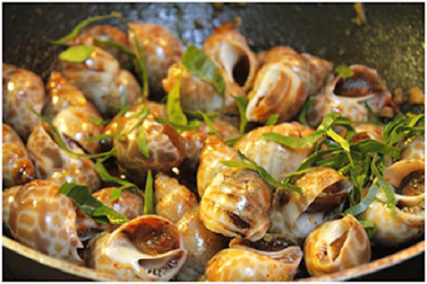 Cuối cùng bạn tắt bếp, rắc một ít lá chanh lên bề mặt ốc, dùng đũa đảo đều, múc ra đĩa dùng nóng cùng cơm hay nhâm nhi với chút bia lạnh sẽ rất tuyệt. (Ảnh: 123amthuc.com)