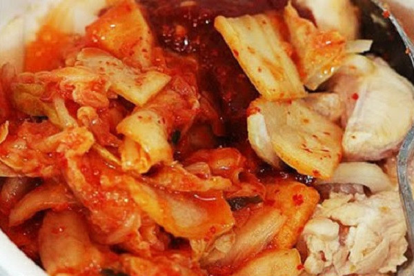 Đến khi thịt vừa săn lại, bạn cho hành tây, kimchi và sốt Gochujang vào đảo nhanh tay cho kim chi ngấm gia vị từ thịt và thịt có màu của kim chi cho ngon mắt. Cho vào nồi khoảng 300ml nước lọc, đun to lửa đến khi sôi. (Ảnh: toinayangi.com)