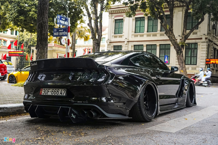 Chiếc Mustang GT tại Hà Nội này được trang bị các vòm bánh xe rộng hơn, được bắt vào thân bằng dàn đinh tán. Chi tiết đinh tán làm chúng ta liên tưởng đến thương hiệu Liberty Walk - hãng độ được biết đến nhiều nhất tại Việt Nam. Tuy nhiên, gói độ này đến từ thương hiệu khá lạ lẫm - Clinched Flares.