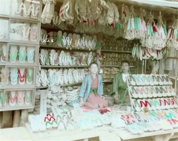 Hai người đàn ông đang ngồi trong gian hàng bán dép, guốc. Ảnh: sohu.com.