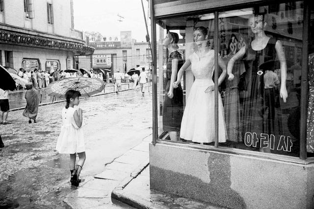 Bé gái Hàn Quốc đứng trước một cửa hàng thời trang trên đường phố Seoul. Ảnh: sina.com.cn.