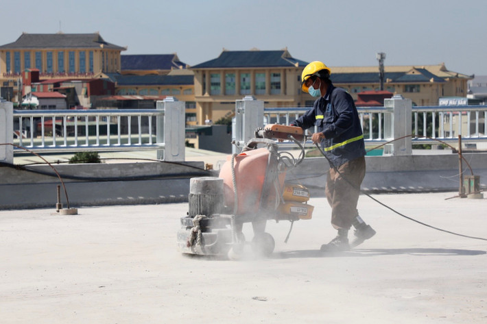 Công nhân thổi bụi, cào đá sỏi ở phần đường chưa trải nhựa.
