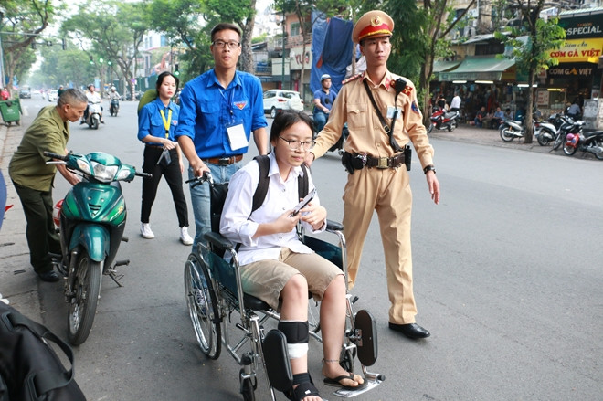Hình ảnh cô nữ sinh ngồi xe lăn dự thi khiến nhiều người xúc động, em được thanh niên tình nguyện và cảnh sát giao thông trợ giúp vào phòng thi.
