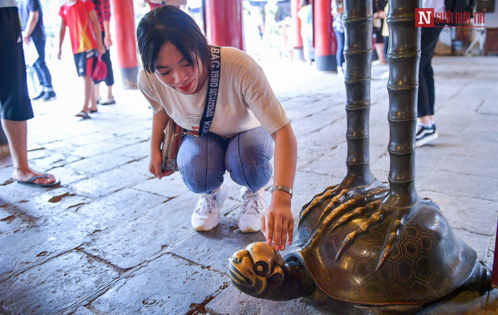 Có người không xoa đầu rùa ở bia đá mà xoa hẳn đầu rùa ở bức tượng đồng rùa cõng chim hạc trong gian lễ, khiến đầu rùa nhẵn bóng. (Ảnh: Người đưa tin)