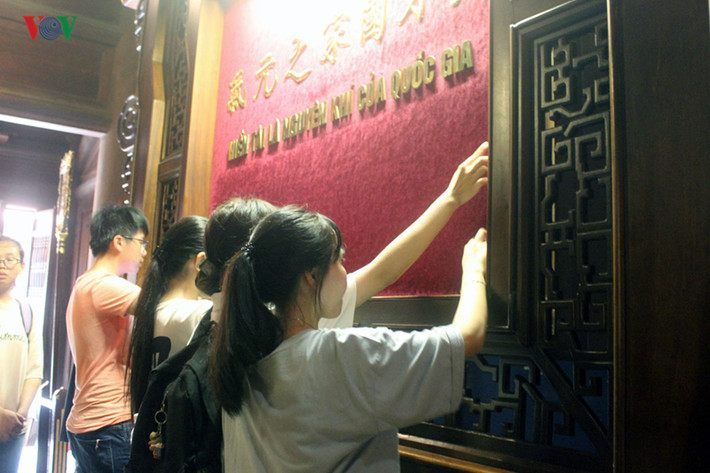 Sĩ tử dùng tay viết tên mình trên bảng Hiền tài là nguyên khí quốc gia. (Ảnh: VOV)