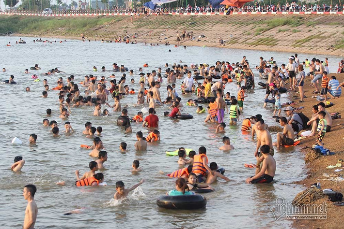 Đập Quán Trăn trở thành “bãi tắm” như ở ngoài biển vài năm gần đây Bên dưới đập, hàng trăm người đủ các lứa tuổi bơi và nghịch nước. Thanh niên trai tráng tự tin bơi ra giữa đập, nơi mực nước sâu nhất. Còn những phụ huynh đưa con nhỏ và gia đình đi tắm chỉ ở gần bờ. Dù đã trang bị áo phao cẩn thận cho các con, nhưng nhiều phụ huynh vẫn phải ngồi trên bờ theo dõi từng động tác của con dưới nước để đảm bảo an toàn.