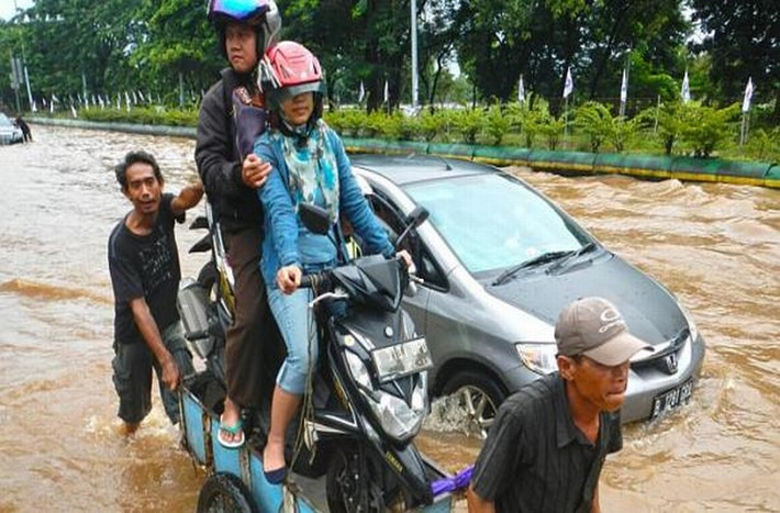 Cặp đôi này thì đang bảo vệ bản thân và tài sản bằng cách cột chặt xe máy lên 1 chiếc xe chở đồ và ngồi trên yên xe để 2 người khác đẩy qua dòng nước lũ ngày 10/2/2015.