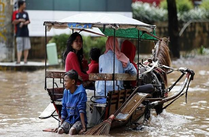 Người dân ngồi trên xe ngựa kéo để di chuyển sau khi những cơn mưa lớn gây ngập lụt nhiều khu vực của thành phố Jakarta ngày 10/2/2015.