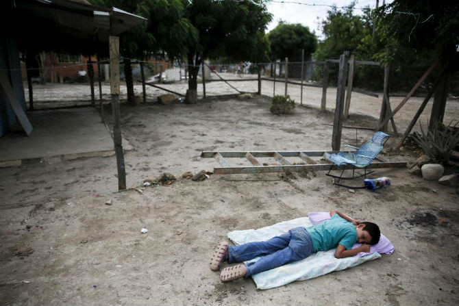 Bé trai nằm trên nền đất trong căn nhà trống không đã bị tháo dỡ ở San Antonio, Tachira, Venezuela.