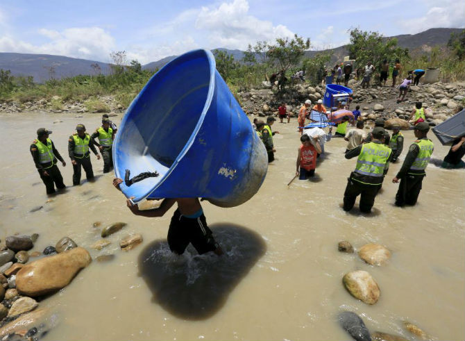 Người dân mang theo các vật dụng vượt qua dòng sông Tachira để về Colombia ngày 25/8/2015.