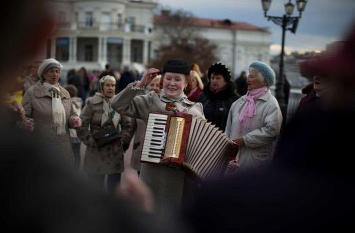 Người phụ nữ lớn tuổi chơi đàn accordion khi bạn bè của bà tận hưởng 1 buổi tối ấm áp ở thành phố Sevastopol, Crimea ngày 26/10/2014.