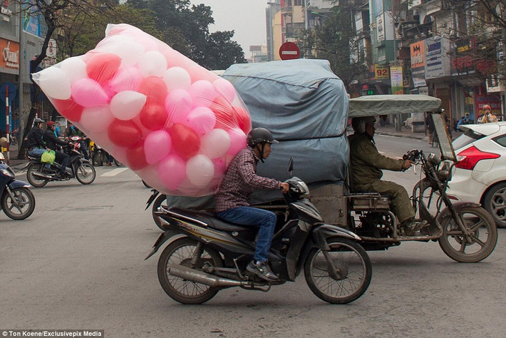Một túi bóng khổng lồ sau lưng người đàn ông đang điều khiển chiếc xe máy trên đường phố Việt Nam.