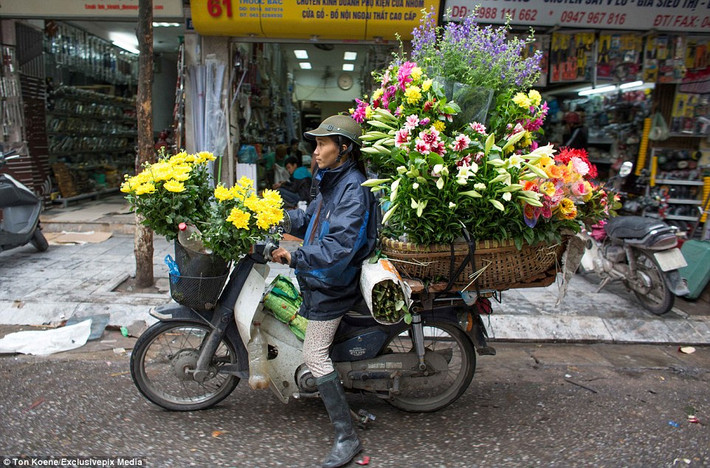 Một người phụ nữ chở đầy hoa đi bán. Việt Nam có khoảng hơn 37 triệu chiếc xe máy.