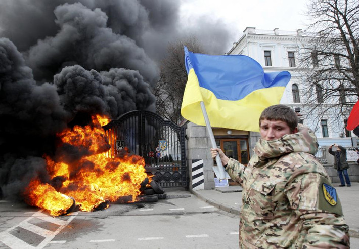 Biểu tình chống giải tán Aydar. Một người lính thuộc tiểu đoàn "Aydar" giơ cao quốc kỳ Ukraine trong một cuộc biểu tình nhằm chống lại việc giải tán tiểu đoàn trước Bộ Quốc phòng Ukraine.
