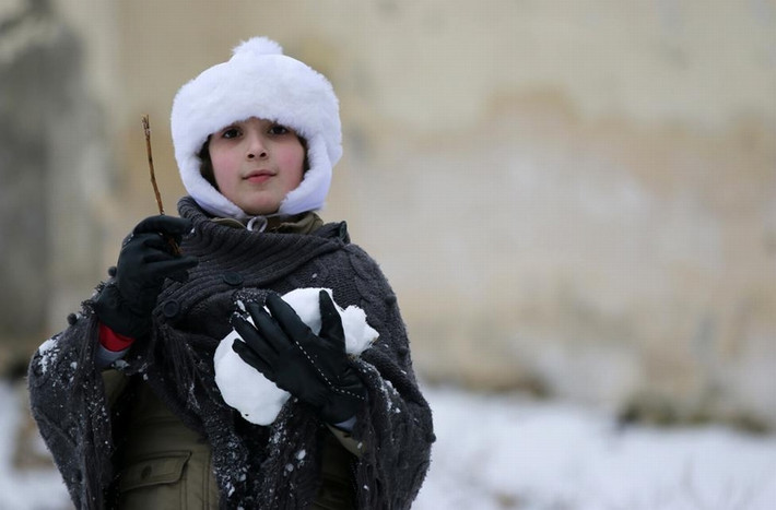1 cô bé ôm quả cầu tuyết khi chơi đùa ở thành phố Aleppo, Syria ngày 11/1/2015.
