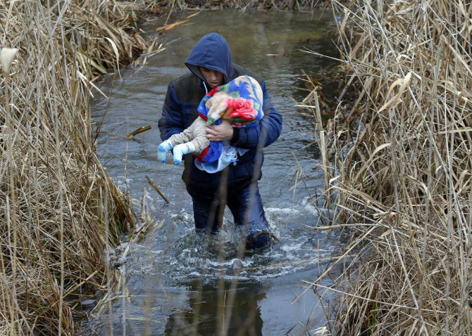 Một người đàn ông Kosovo bế con nhỏ trên tay vượt biên giới Hungary – Serbia ngày 6/2/2015.