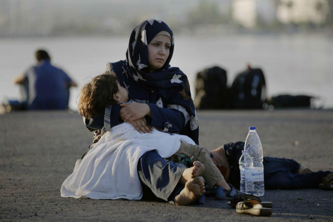 Một người dân tị nạn Syria ngồi ôm con nhỏ tại cảng biển ở đảo Kos, Hy Lạp ngày 15/8.