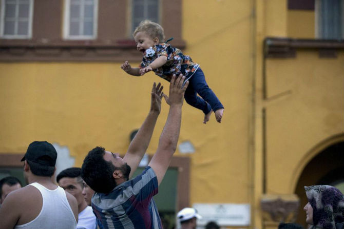 Một di dân chơi đùa cùng con nhỏ khi họ chờ lên chuyến tàu tới nhà ga Gevgelija ở Macedonia ngày 14/8.