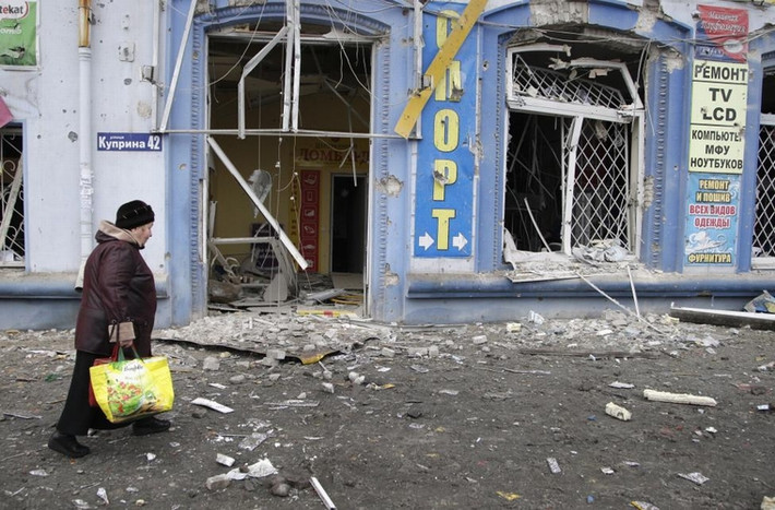 Người phụ nữ đi ngang qua 1 tòa nhà bị phá hủy gần bến xe buýt ở Donetsk, Ukraine ngày 22/1/2015.
