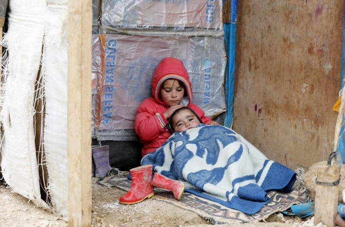 1 cô bé tị nạn người Syria ngồi cùng em trai ở 1 khu vực định cư tạm thời ở thành phố Bar Elias trong thung lũng Bekaa, Lebanon ngày 5/1/2015.