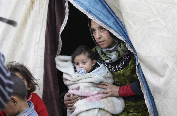 Người phụ nữ bế 1 đứa trẻ trong khu trại tị nạn Al-Karameh giáp biên giới Syria-Thổ Nhĩ Kỳ ở phía bắc thành phố Idlib, Syria ngày 10/1/2015.