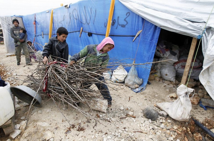 Những cậu bé tị nạn người Syria mang củi vào lều để đốt sưởi ấm trong 1 khu định cư tạm thời ở thành phố Bar Elias, trong thung lũng Bekaa, Lebanon ngày 5/1/2015.