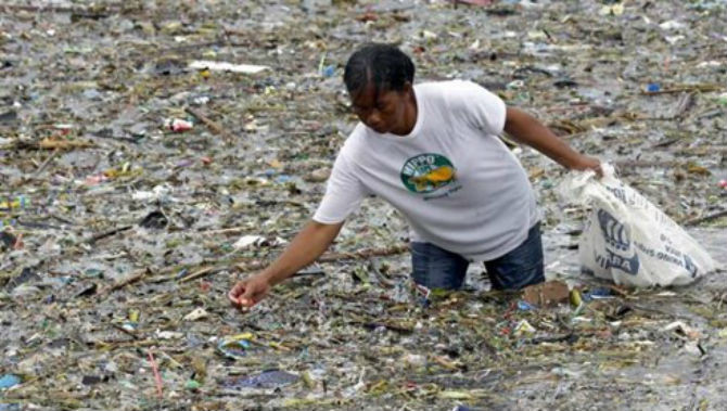 Một người dân Philippines lượm lặt và sửa những món đồ bị mưa bão cuốn trôi theo cơn sóng tại một khu vực ven biển ở thành phố Pasay, phía nam Manila, Philippines, ngày 22/8/2015. (Ảnh EFE).