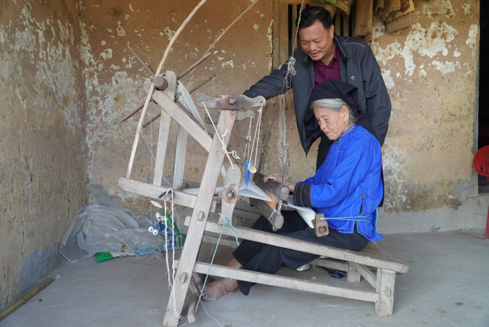 Bên nếp nhà trình tường đơn sơ, cụ bà Vi Thị Thêm (80 tuổi) vẫn ngày ngày dệt những tấm khăn, áo chàm.
