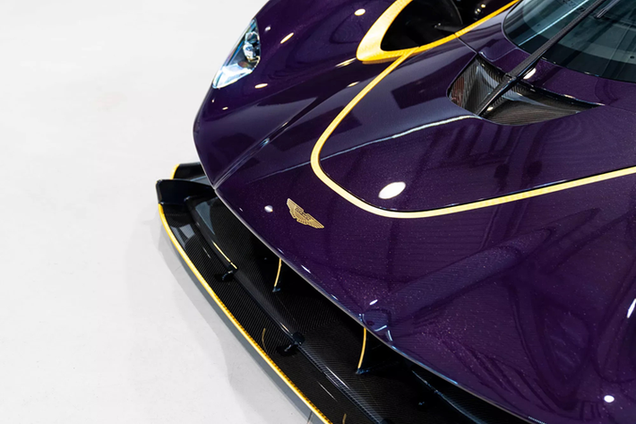 Logo Aston Martin làm màu vàng, bộ mâm nhôm màu đen satin kết hợp điểm nhấn màu vàng, phần nóc xe và nắp che động cơ được làm từ sợi carbon. Toàn bộ thân xe được bọc bằng phim bảo vệ PPF, giúp giữ bề mặt đặc biệt này không bị trầy xước hay mẻ sơn.