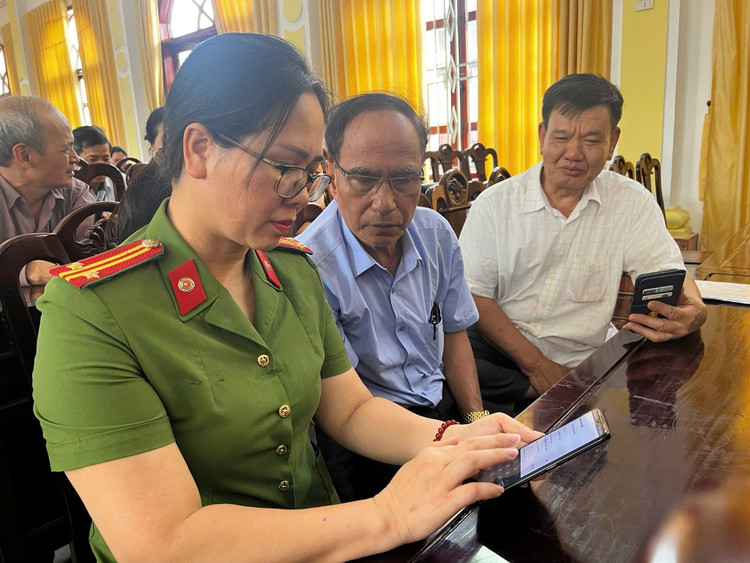Cán bộ Phòng Cảnh sát quản lý hành chính về trật tự xã hội hướng dẫn người dân thực hiện thao tác tham gia ý kiến qua ứng dụng VNeID. 99887.jpg