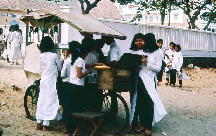 Các nữ sinh tụ tập bên quầy bánh mì bên ngoài một ngôi trường ở Vũng Tàu. Ảnh: Terry Maher.