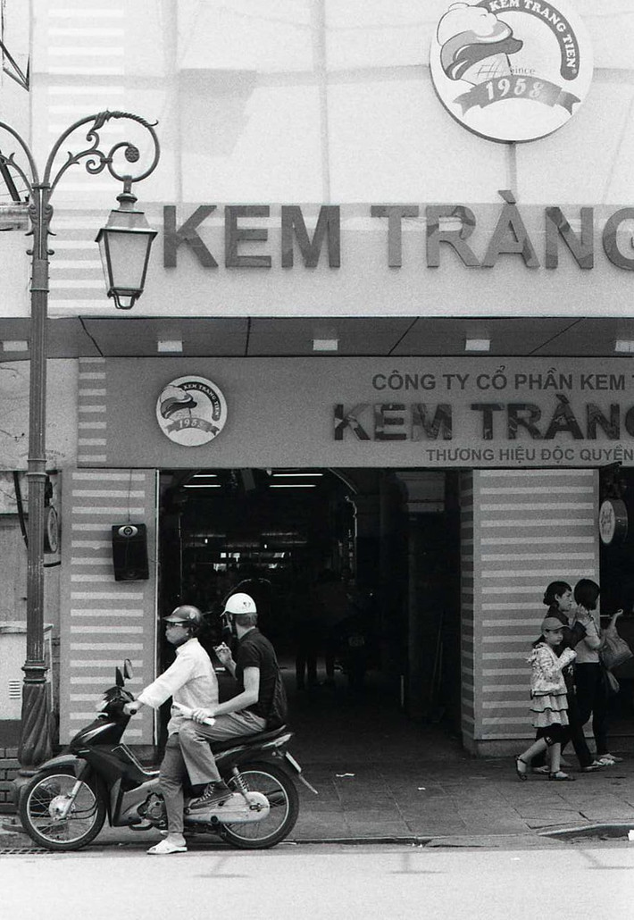 Kem Tràng Tiền thời điểm năm 2013. Lúc này tên cửa hàng không còn hai chữ "đặc biệt". Khách mua kem đã có chỗ để xe bên trong cửa hàng. Tên công ty chủ quản đã liên tục thay đổi theo các năm. Ảnh: Yuichi Kobayashi.