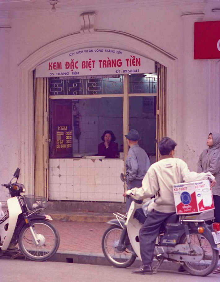 Một hình ảnh khác về hiệu kem Tràng Tiền năm 1998. Ảnh chụp vào một ngày mùa đông giá lạnh và cửa hàng có vẻ khá vắng khách. Lúc này kem đậu xanh có giá 2.000 đồng. Kem sô cô la và ốc quế giá 3.000 đồng. Ảnh: Yuichi Kobayashi.