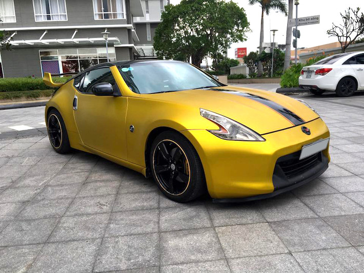 Vốn có số lượng rất ít tại Việt Nam, nhưng chiếc 370Z tại Sài Gòn này còn được chủ xe "trang điểm" với một số chi tiết nổi bật. Đầu tiên, toàn bộ thân xe đã được dán trong tông màu vàng mờ ánh kim - đen bóng nổi bật.