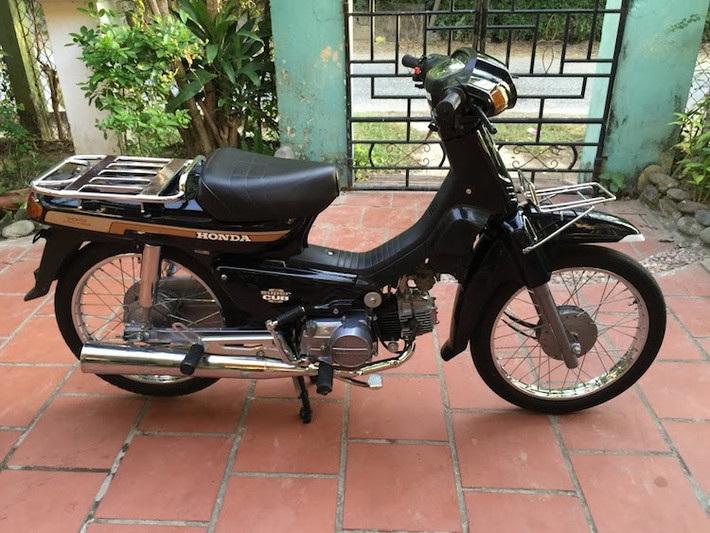 Vốn được bán với yếm màu trắng ngà kèm theo, tuy nhiên chiếc Cub Custom 100 này đã được chủ nhân tạm thay yếm cắt màu đen để có thể nhìn rõ được khối động cơ "hàng hiếm" gần như mới của nó.