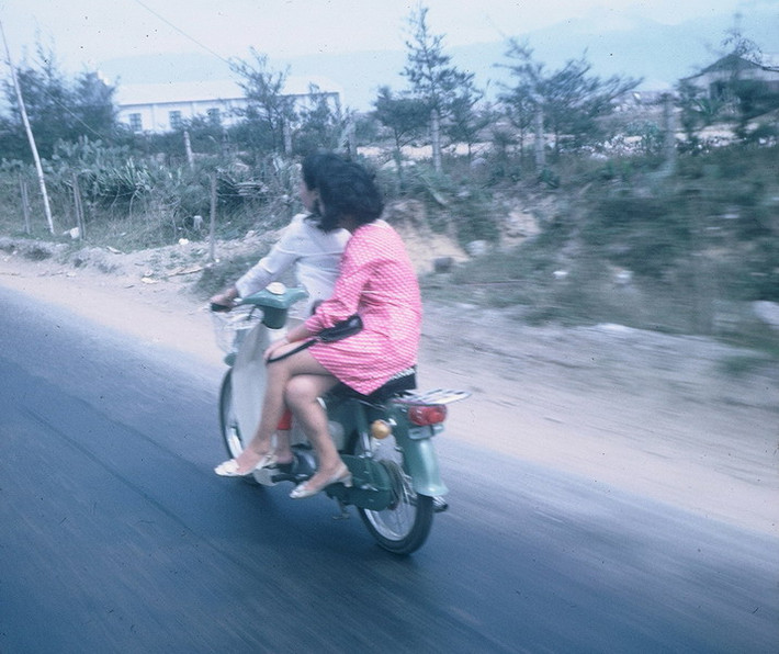 Một cặp đôi chở nhau trên đường bằng xe Honda Cub.