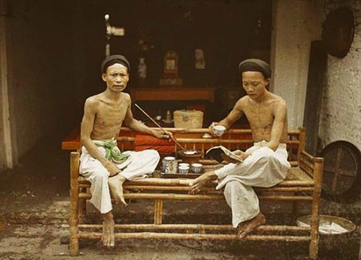 Hai người Việt ngồi uống trà và hút thuốc lào trong một tiệm hút ở Hà Nội năm 1915. Ảnh: Léon Busy.