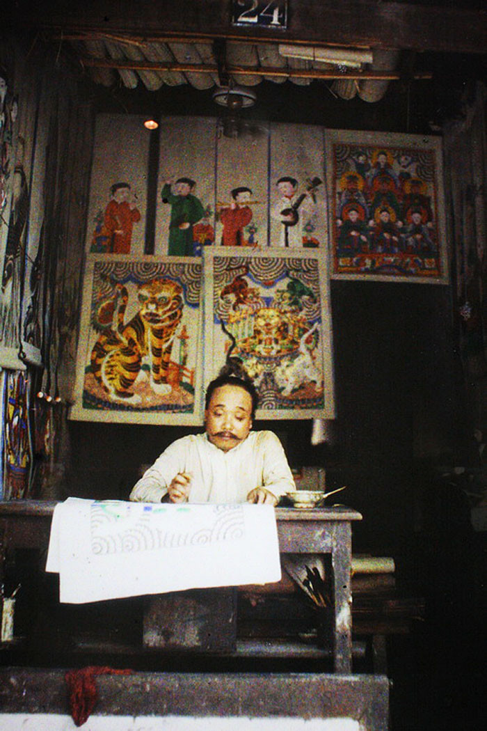 Nghệ nhân ngồi vẽ tranh tại phố Hàng Trống, Hà Nội. Ảnh: Léon Busy.