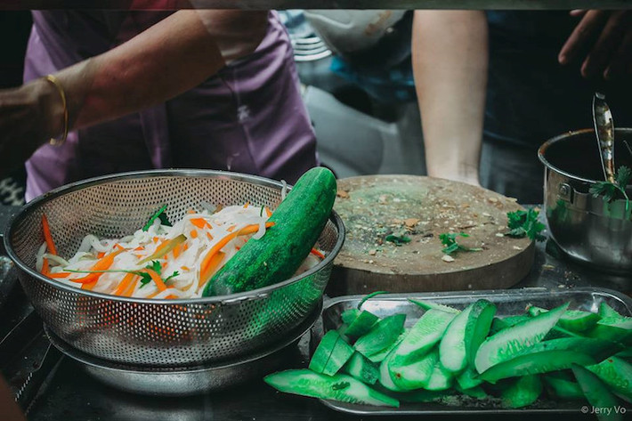Một ổ bánh mì có các loại dưa chua, dưa leo, hành ngò, với 5 viên thịt nướng cùng nước sốt đậm đà.