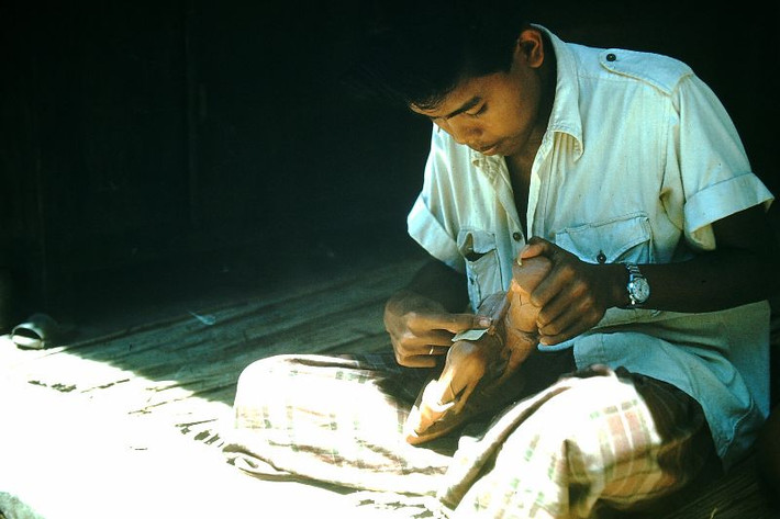 Người thợ mộc mài giũa bức tượng gỗ của mình. Ảnh: Found Slides.