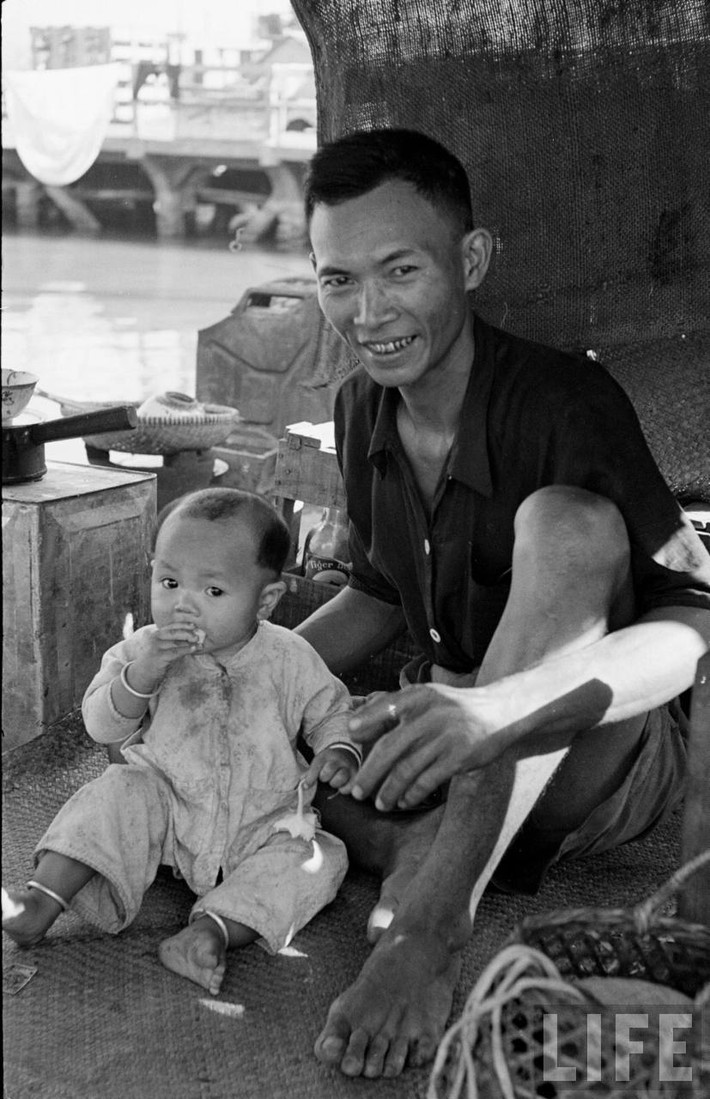 Hai bố con dân xóm chài bên trong "ngôi nhà" nổi. Ảnh: Carl Mydans/ Life.