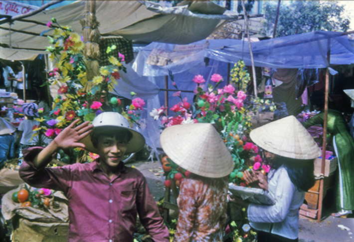 Cậu bé bán hoa tạo dáng khi được chụp ảnh ở chợ Tết Nha Trang. Ảnh: Vietnam Center and Archive.