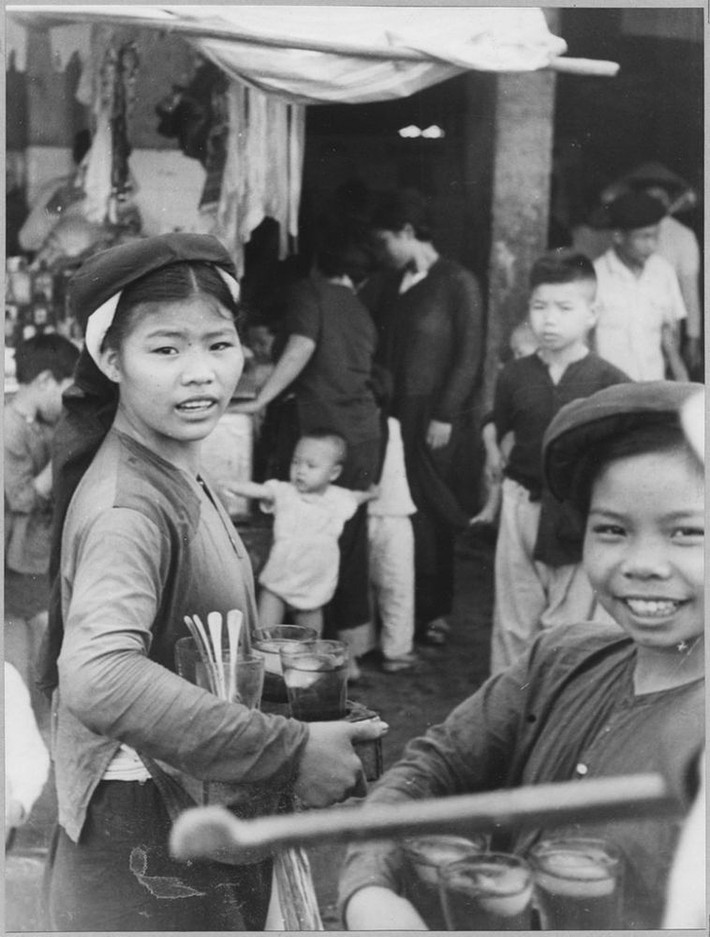 Hai cô cái bán nước ngọt đựng trong cốc thủy tinh.